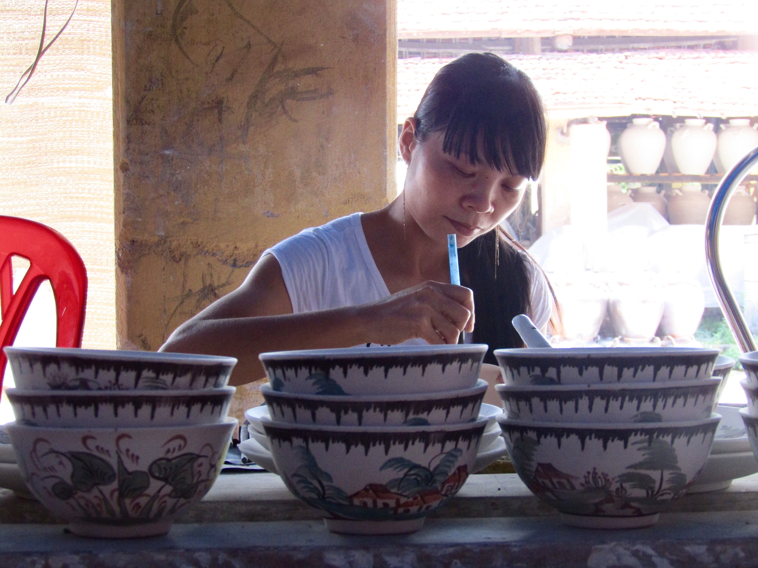 Inside, a woman puts the finishing touches on one of the ceramic bowls. She worked quickly and precisely, creating a unique scene on each piece.